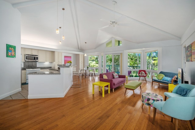 living room with beam ceiling, high vaulted ceiling, light hardwood / wood-style flooring, and a wealth of natural light