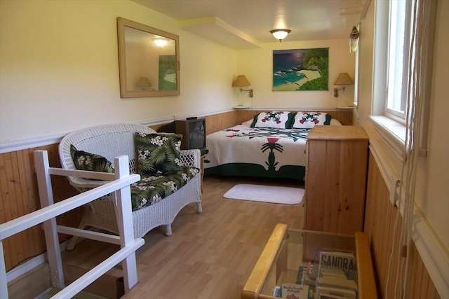 bedroom featuring light hardwood / wood-style floors and wood walls