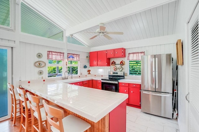 kitchen featuring ceiling fan, tasteful backsplash, vaulted ceiling with beams, kitchen peninsula, and appliances with stainless steel finishes