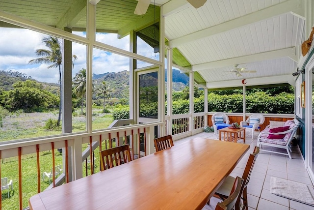 sunroom / solarium featuring ceiling fan, a mountain view, and lofted ceiling with beams