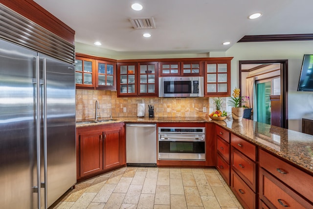 kitchen featuring backsplash, stone counters, crown molding, sink, and stainless steel appliances