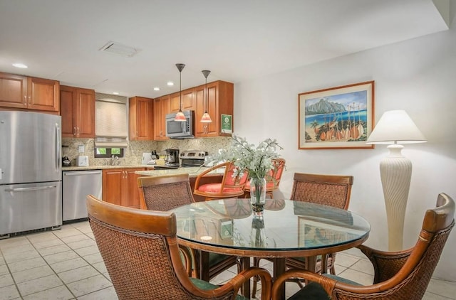 kitchen featuring pendant lighting, sink, light tile patterned floors, appliances with stainless steel finishes, and tasteful backsplash