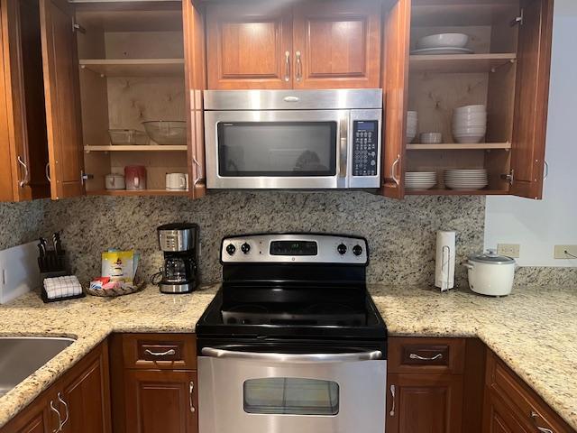 kitchen featuring decorative backsplash, light stone countertops, and appliances with stainless steel finishes