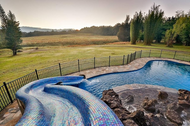 view of pool featuring a lawn and a rural view