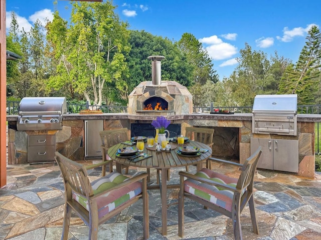 view of patio with an outdoor stone fireplace, area for grilling, and exterior kitchen