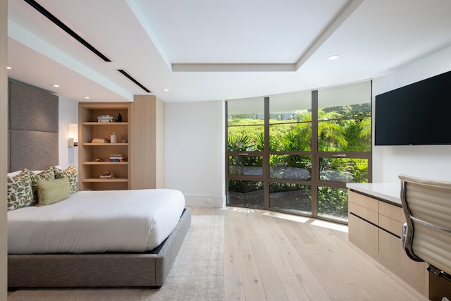 bedroom featuring multiple windows, floor to ceiling windows, and light wood-type flooring