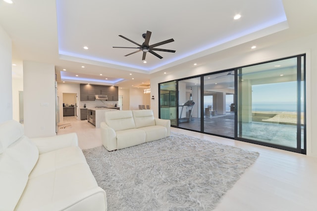 living room with ceiling fan and a raised ceiling