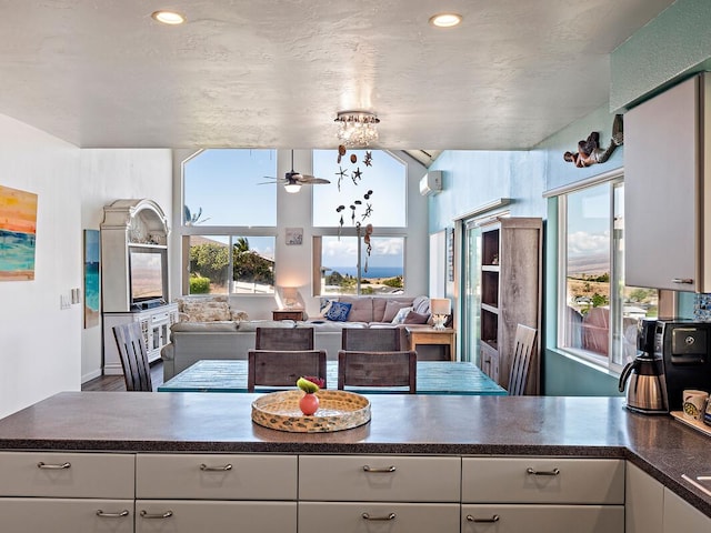 kitchen with white cabinetry and ceiling fan with notable chandelier