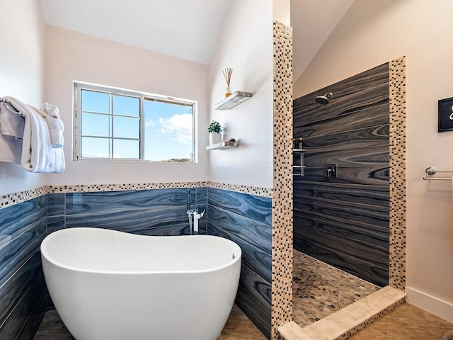 bathroom featuring tile patterned flooring, lofted ceiling, tile walls, and independent shower and bath