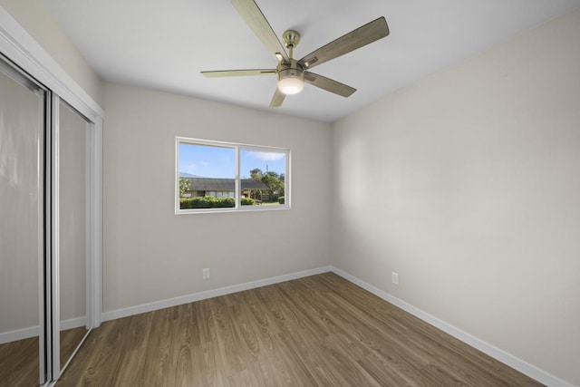 unfurnished bedroom featuring ceiling fan, a closet, and hardwood / wood-style floors