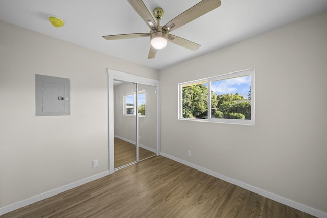 unfurnished bedroom featuring a closet, electric panel, ceiling fan, and hardwood / wood-style flooring