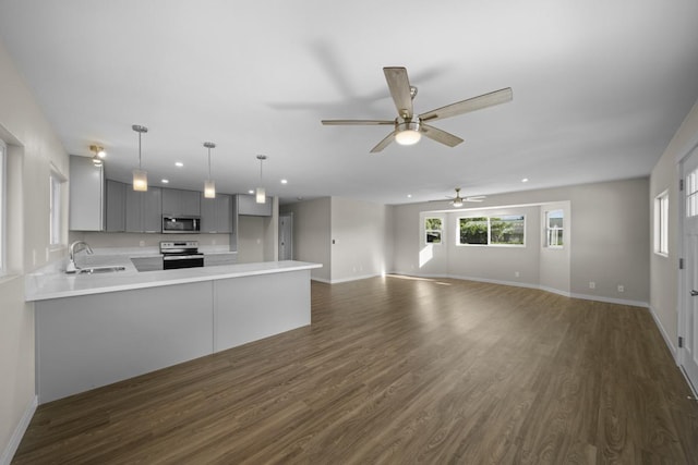 kitchen with kitchen peninsula, gray cabinetry, stainless steel appliances, dark wood-type flooring, and decorative light fixtures