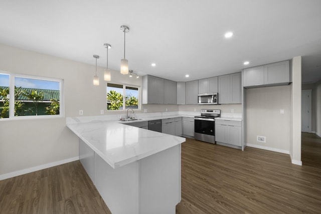 kitchen with kitchen peninsula, stainless steel appliances, sink, decorative light fixtures, and dark hardwood / wood-style floors