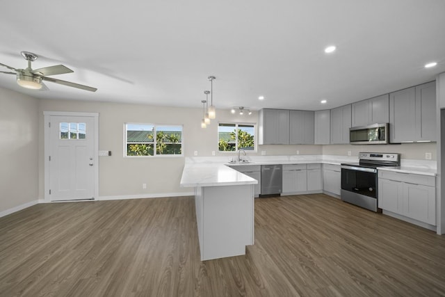 kitchen featuring ceiling fan, sink, dark wood-type flooring, kitchen peninsula, and appliances with stainless steel finishes