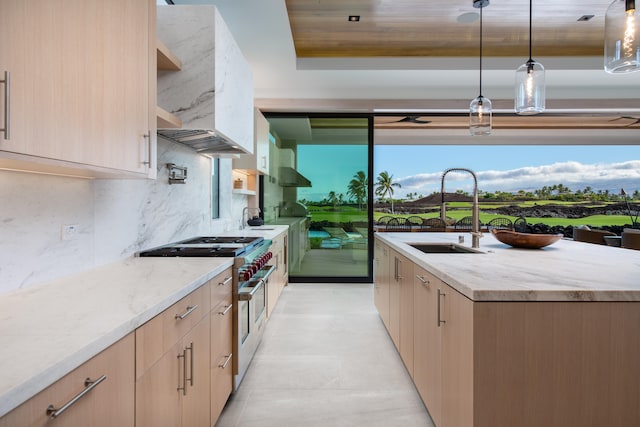 kitchen featuring sink, range with two ovens, decorative light fixtures, light brown cabinetry, and exhaust hood