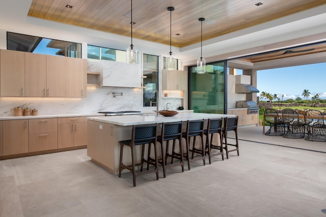 kitchen featuring light brown cabinets, a raised ceiling, decorative light fixtures, a kitchen island, and wood ceiling