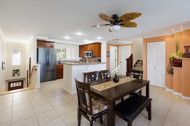 tiled dining area featuring crown molding and ceiling fan