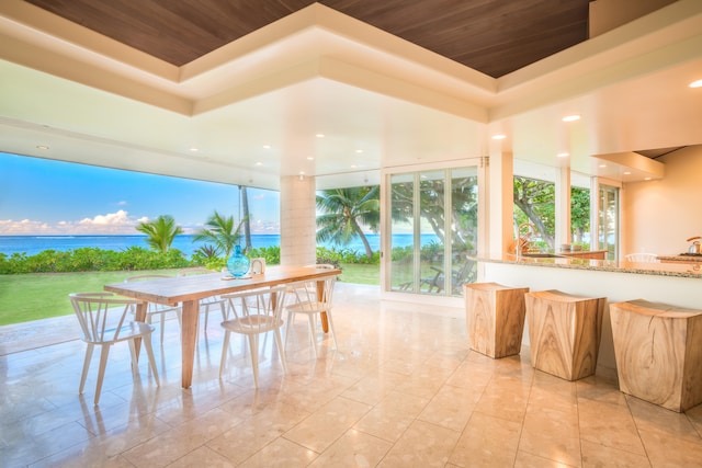 interior space with a water view, a raised ceiling, and wood ceiling