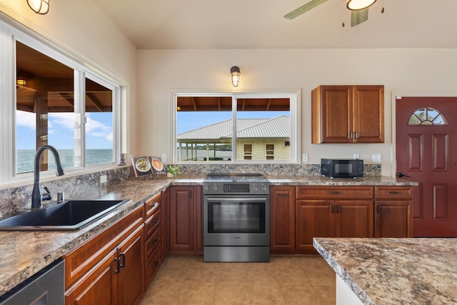 kitchen featuring stainless steel appliances, ceiling fan, sink, light tile patterned floors, and a water view