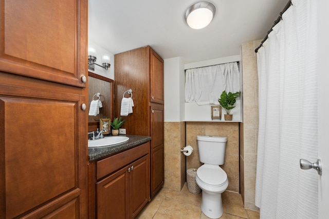 bathroom featuring tile patterned floors, vanity, toilet, and tile walls