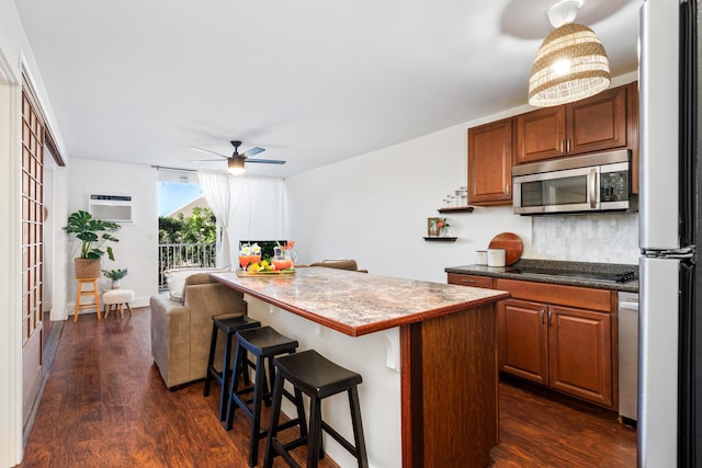 kitchen with a kitchen bar, appliances with stainless steel finishes, a center island, and dark hardwood / wood-style flooring