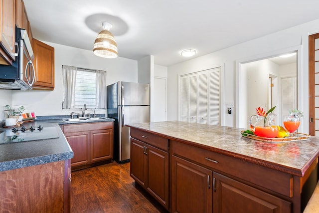 kitchen featuring dark wood-type flooring, a center island, stainless steel appliances, and sink