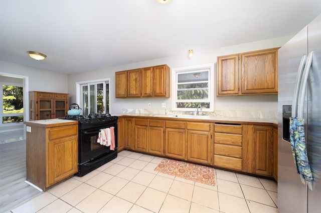 kitchen with a healthy amount of sunlight, black range with gas stovetop, sink, and stainless steel fridge with ice dispenser