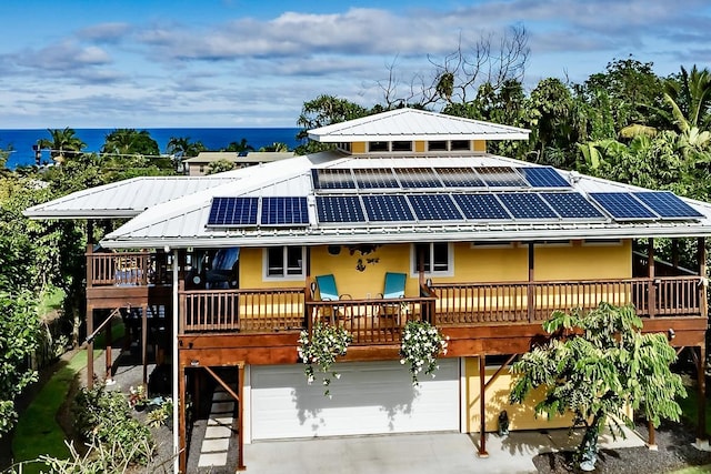 view of front of property with a garage, a deck with water view, and solar panels