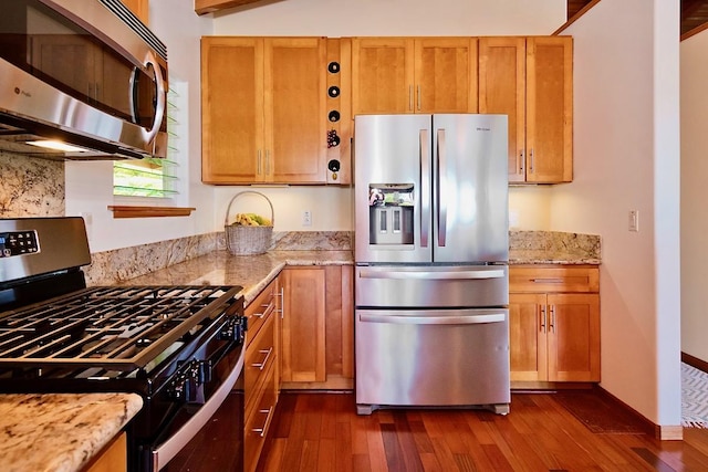 kitchen featuring appliances with stainless steel finishes, dark wood-type flooring, light stone counters, and decorative backsplash