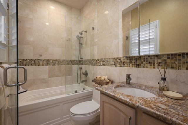 full bathroom with decorative backsplash, vanity, shower / bath combination with glass door, tile walls, and toilet