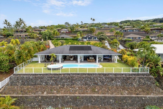 rear view of property featuring outdoor lounge area, solar panels, a patio area, and a lawn