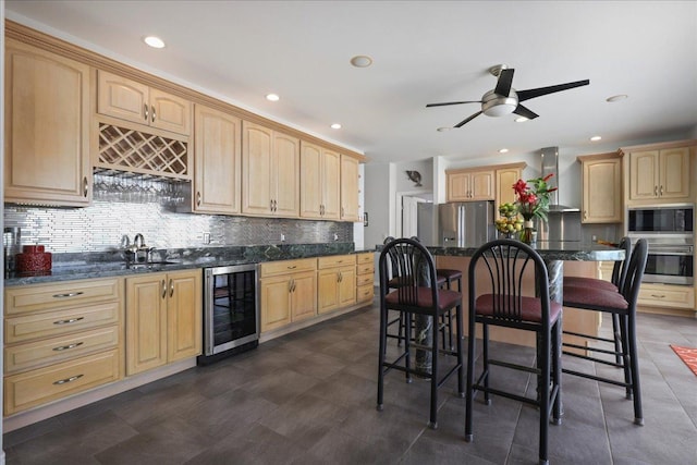 kitchen with a breakfast bar, a center island, wall chimney range hood, stainless steel appliances, and beverage cooler