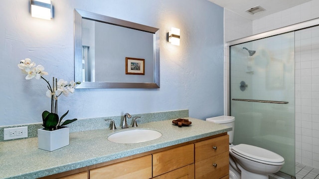 bathroom with vanity, toilet, and a shower with door