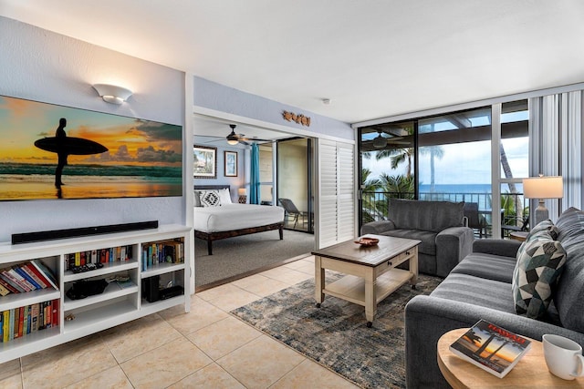 living room featuring light tile patterned floors, a water view, expansive windows, and ceiling fan