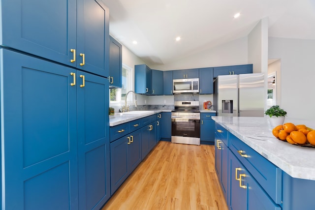 kitchen with lofted ceiling, blue cabinets, sink, light wood-type flooring, and appliances with stainless steel finishes