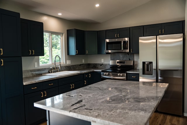 kitchen featuring light stone countertops, lofted ceiling, sink, and appliances with stainless steel finishes