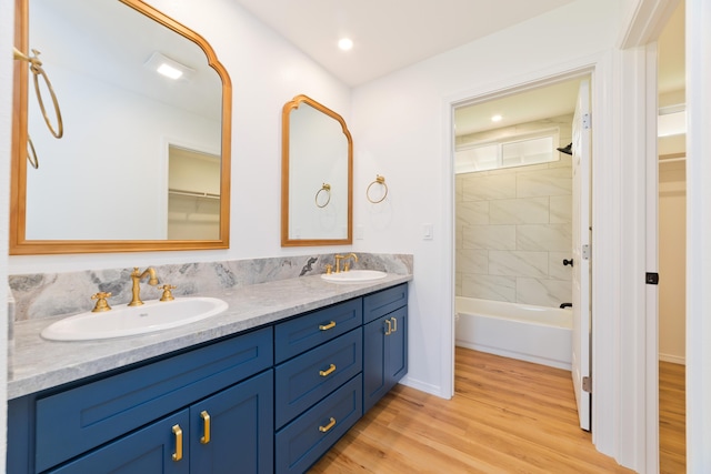 bathroom with hardwood / wood-style floors, vanity, and tiled shower / bath