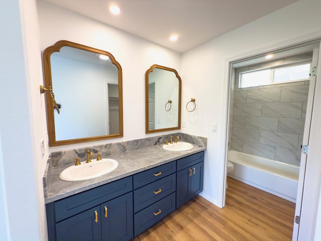 full bathroom featuring wood-type flooring, vanity, toilet, and tiled shower / bath combo