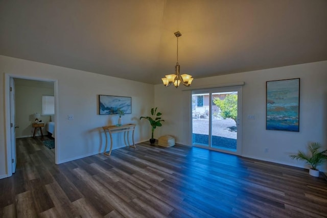 empty room featuring dark hardwood / wood-style floors, vaulted ceiling, and a notable chandelier