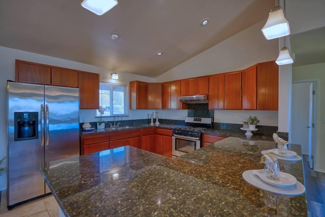 kitchen featuring sink, dark stone counters, decorative light fixtures, vaulted ceiling, and appliances with stainless steel finishes