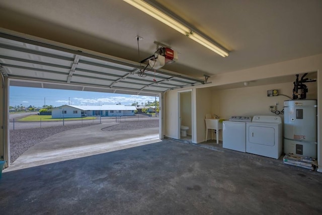 garage featuring washing machine and dryer, sink, and strapped water heater