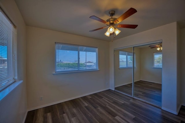 unfurnished bedroom featuring dark hardwood / wood-style flooring, ceiling fan, and a closet