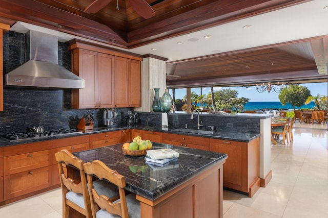 kitchen featuring a water view, wall chimney range hood, sink, tasteful backsplash, and gas cooktop