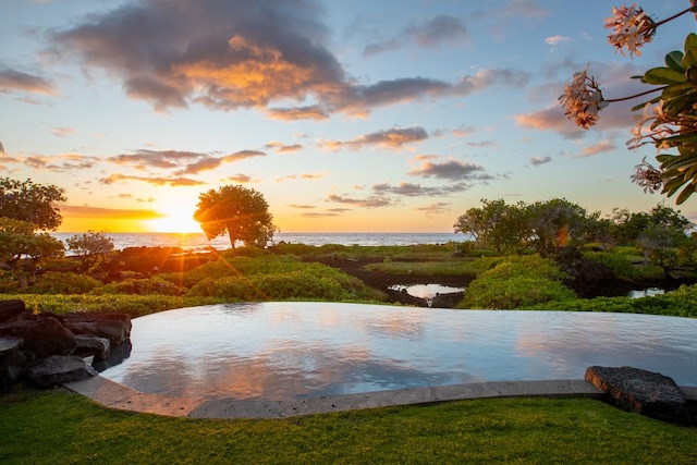 pool at dusk featuring a water view