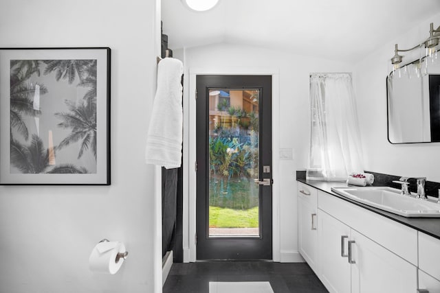 bathroom featuring tile patterned flooring, vanity, and vaulted ceiling