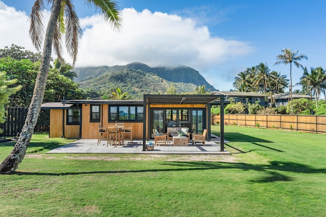 rear view of house with a mountain view, a patio area, and a yard