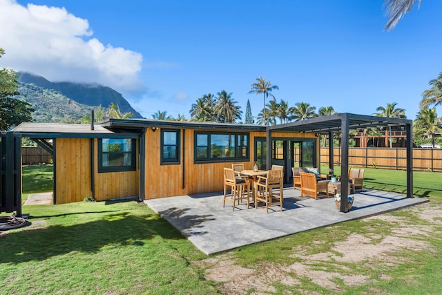 back of property with a pergola, an outdoor hangout area, a patio area, a mountain view, and a yard