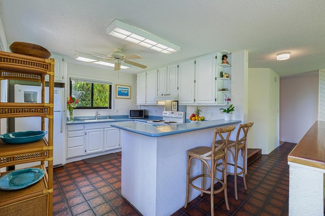 kitchen featuring ceiling fan, sink, kitchen peninsula, white appliances, and white cabinets