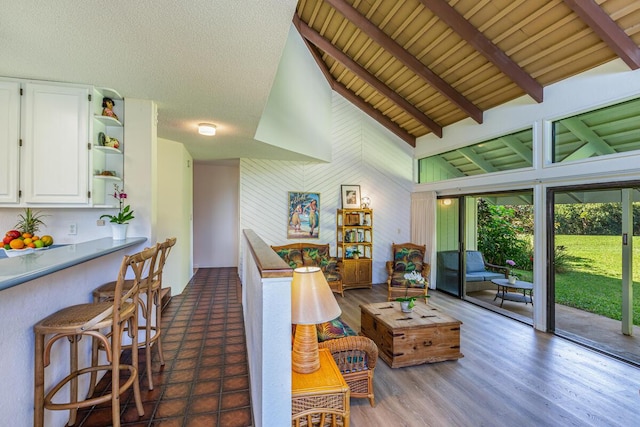 living room featuring dark wood-type flooring, wooden ceiling, beamed ceiling, high vaulted ceiling, and a textured ceiling