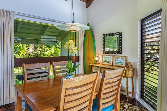 tiled dining room featuring lofted ceiling with beams